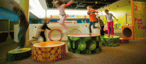 A group of kids jumping in the air at an indoor playground.