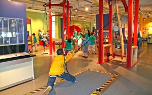 A boy in yellow jacket holding onto ropes.